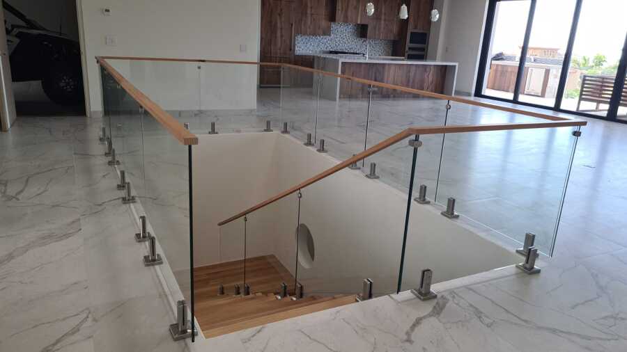 Barandal de cristal templado con pasamanos de madera en cubo de escalera