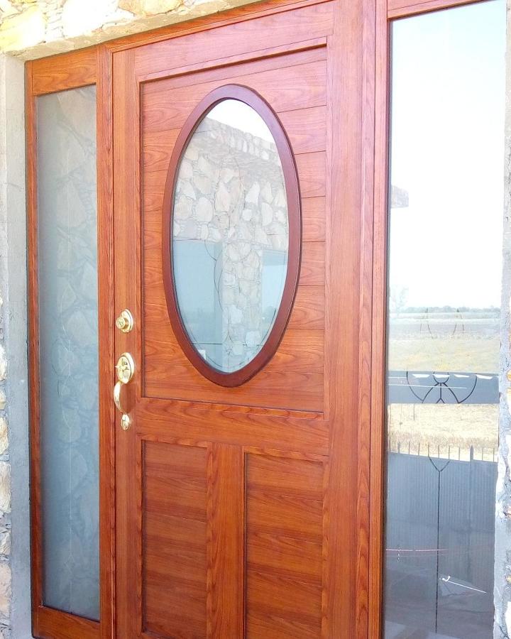 Puerta batiente, en aluminio imitación madera.