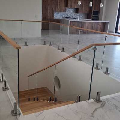 Barandal de cristal templado con pasamanos de madera en cubo de escalera
